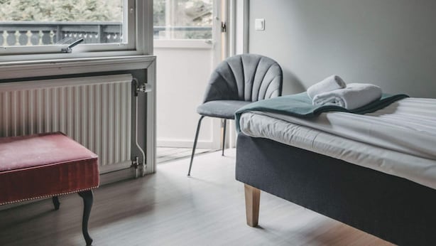 A bedroom with a bed, a chair, a bench, and a window with a view of trees. - 4 Star Holiday Home in Hisings Backa (Hisings Backa)