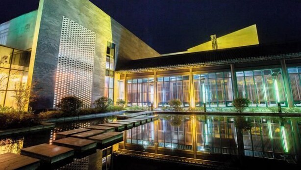 A modern building with a reflective pool and a well-lit facade.