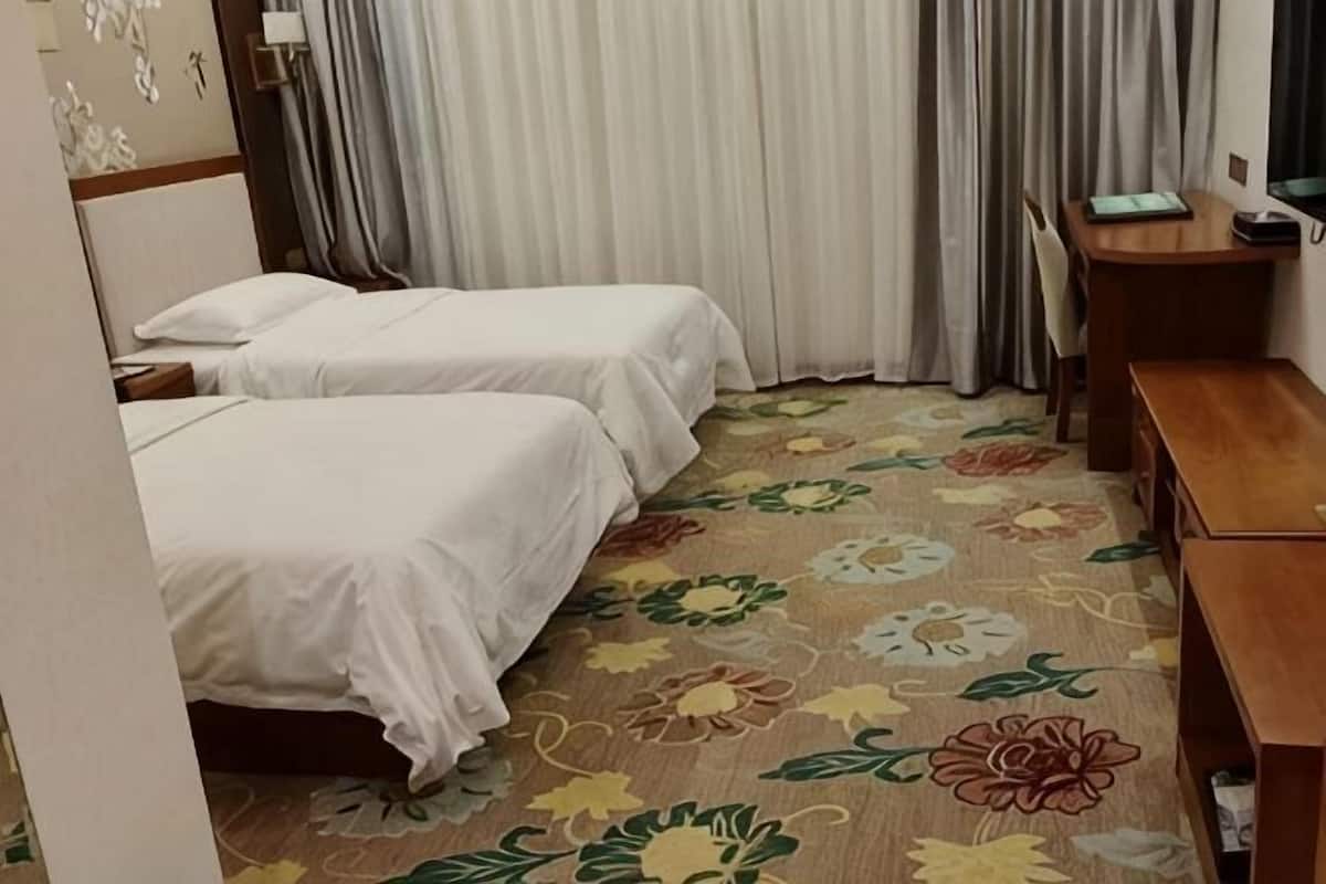 Habitació d'hotel amb dos llits, una taula i una cadira.