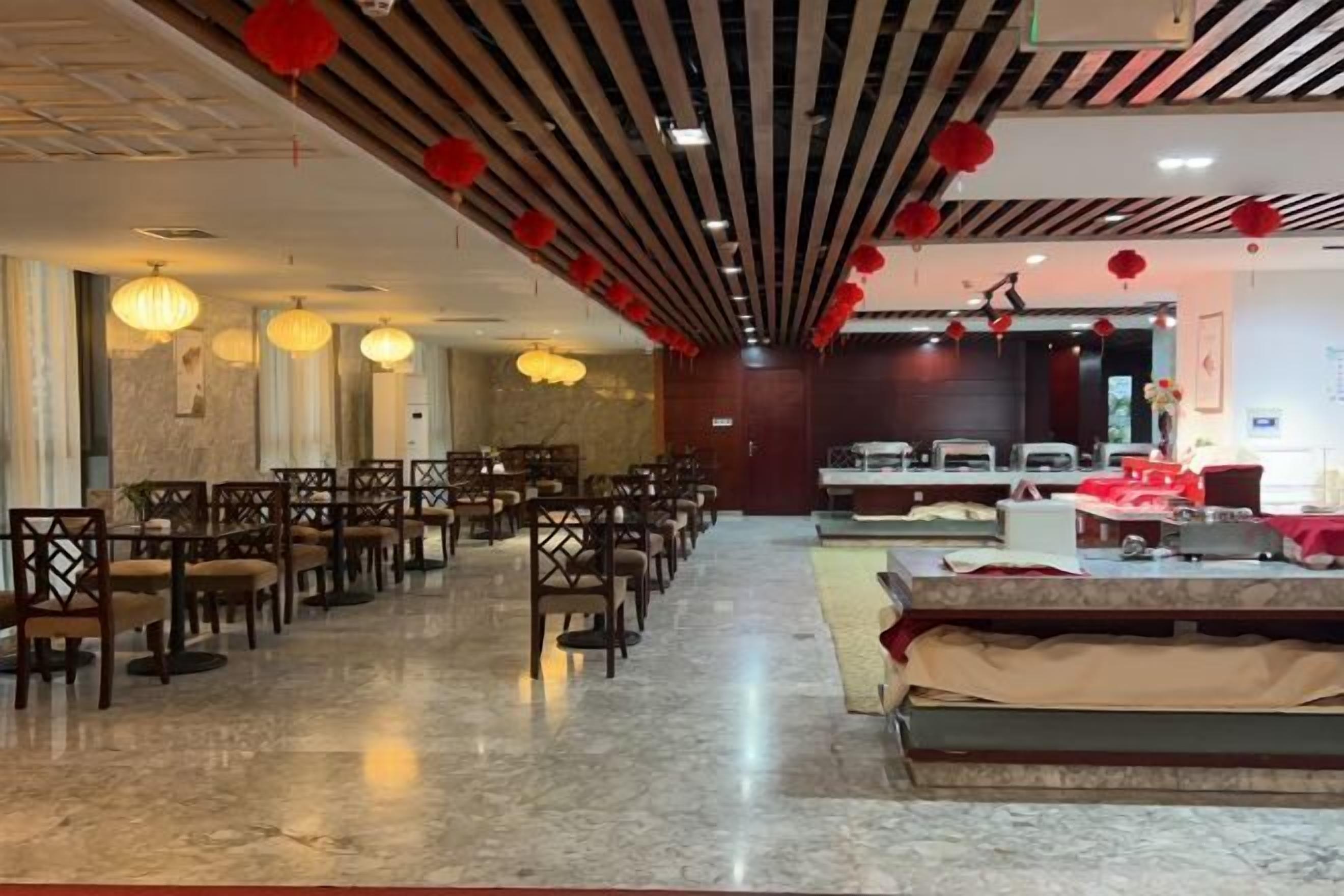 Un hall d’hôtel spacieux, doté d’un sol en marbre, de chaises et de tables en bois.