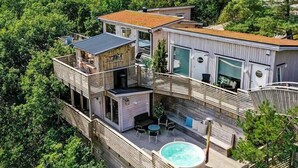 Un immeuble résidentiel à plusieurs étages doté d’un jacuzzi sur le toit, d’un espace extérieur aménagé et offrant une vue sur une zone boisée.