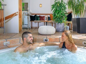 A hot tub with a stone floor, a wooden staircase, and a seating area with cushions and plants. - 4 Star Holiday Home in Hisings Backa (Hisings Backa)