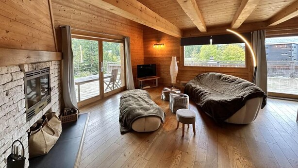 A cozy cabin interior with a stone fireplace, wooden floors, a large bed, and a TV. - Chalet, ski lifts base, sauna, terrace, balcony, fireplace or stove, tv, 160m², Villard de Lans (Corrençon-en-Vercors)