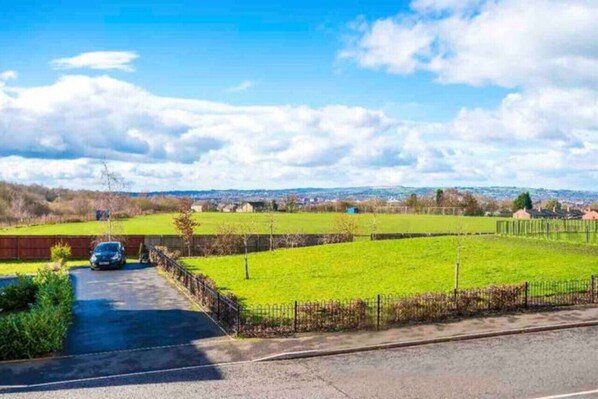 A rural landscape with a paved road, a car, and a grassy field. - Lovely three bed home Manchester (Bury)