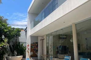 A modern building with a glass facade, outdoor seating area, and potted plants. - Beautiful Bali Villas (Bali)