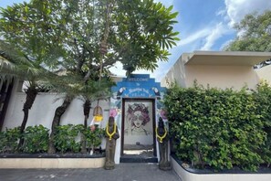 A gated entrance with a 'Welcome' sign, a palm tree, and a hedge. - Beautiful Bali Villas (Bali)
