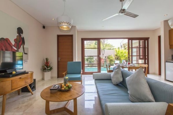 A modern living room with a sofa, a coffee table, a TV, and a dining area with a table and chairs. - Beautiful Bali Villas (Bali)