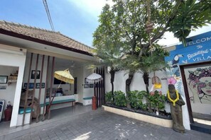 A villa entrance with a tiled roof, a bench, a statue, and a welcome sign. - Beautiful Bali Villas (Bali)
