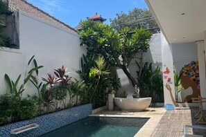 A swimming pool surrounded by plants and a decorative fountain. - Beautiful Bali Villas (Bali)