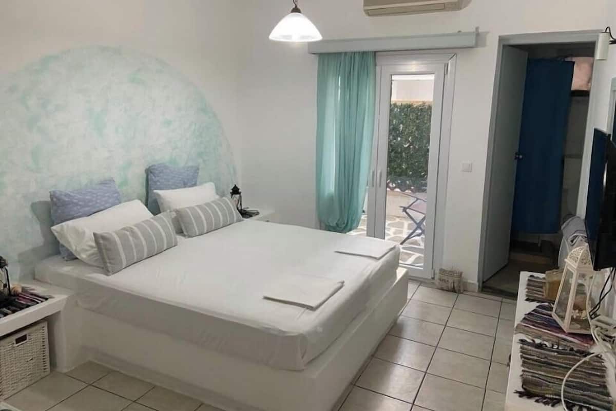A bedroom with a large bed, a nightstand, a lamp, and a view of the outside through a sliding door.