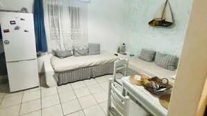 A compact living space with a kitchenette, a dining area, and a seating area with a sofa and a chair. - Casa filareti (Ios)