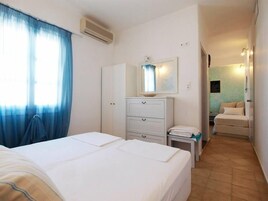 A hotel room with a bed, a bedside table, a dresser, and a bathroom visible through an open door.