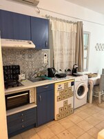 A compact kitchen with a built-in oven, a microwave, a sink, and a washing machine.