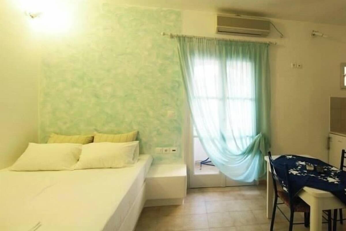 A room with a bed, a small table, and a window with curtains.