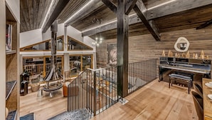 Un loft espaiós amb bigues de fusta a la vista, un piano i un gran finestral amb vista a la ciutat.