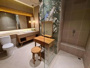 Een moderne badkamer met douche, toilet, wastafel en een klein krukje.