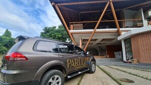 Un SUV marrón estacionado frente a un edificio con balcón y pared de ladrillo.