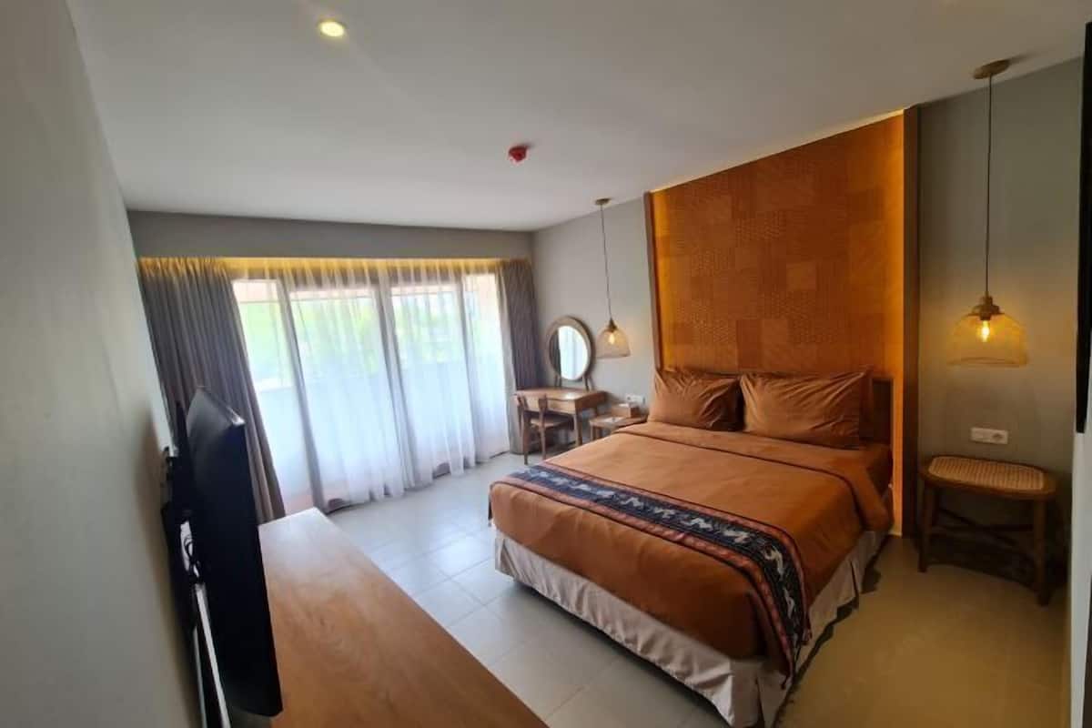 Ein Schlafzimmer mit einem Bett, einem Schreibtisch, einem Stuhl, einem Fernseher und einem Fenster mit Vorhängen.