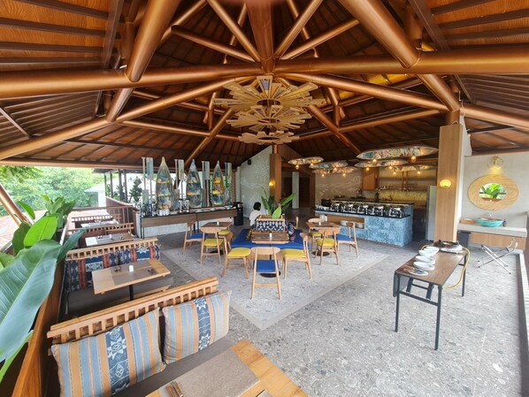 Een ruime binnenruimte met een bar, zitgedeeltes en uitzicht op de omgeving.