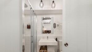 Een moderne badkamer met een douchecabine van glas, een witte wastafel en een spiegel erboven.