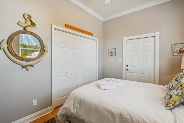 A bedroom with a bed, a round mirror, two white doors, and a small sign above one door. - 30A Beach House - Seagrove Escape by PHG (Santa Rosa Beach)