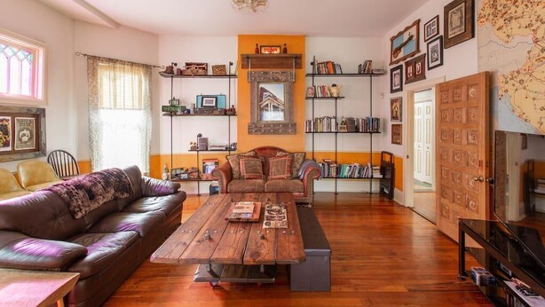 Ein gemütliches Wohnzimmer mit Couchtisch aus Holz, Ledersofa und Bücherregalen voller Bücher und Dekoration.