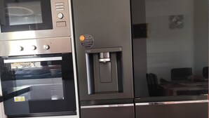 Eine Küche mit Einbau-Mikrowelle, Backofen und Kühlschrank mit Wasserspender.