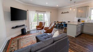 Una sala de estar moderna con un sofá gris, un televisor de pantalla plana y un comedor con mesa y sillas.