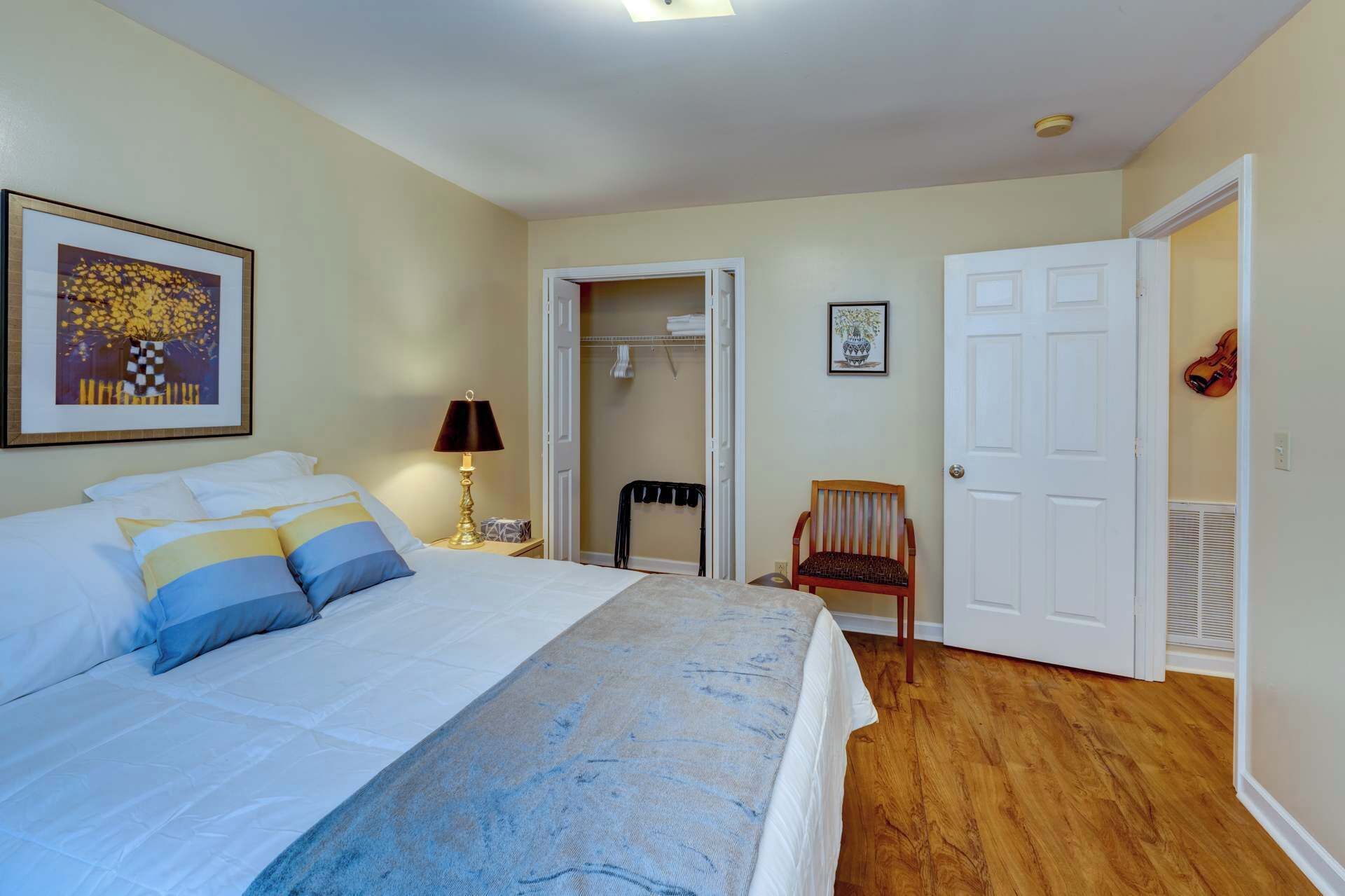 Une chambre à coucher avec un lit, une table de chevet, une lampe, une chaise et une porte.