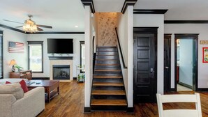 A staircase with a fireplace, a television, and a flag on the wall. - Hello Goodbye | Ultimate Experience! (Nashville)