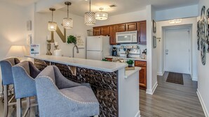A modern kitchen with a central island, bar stools, pendant lighting, and wooden cabinets. - Riverfront Condo Minutes from Broadway (Nashville)