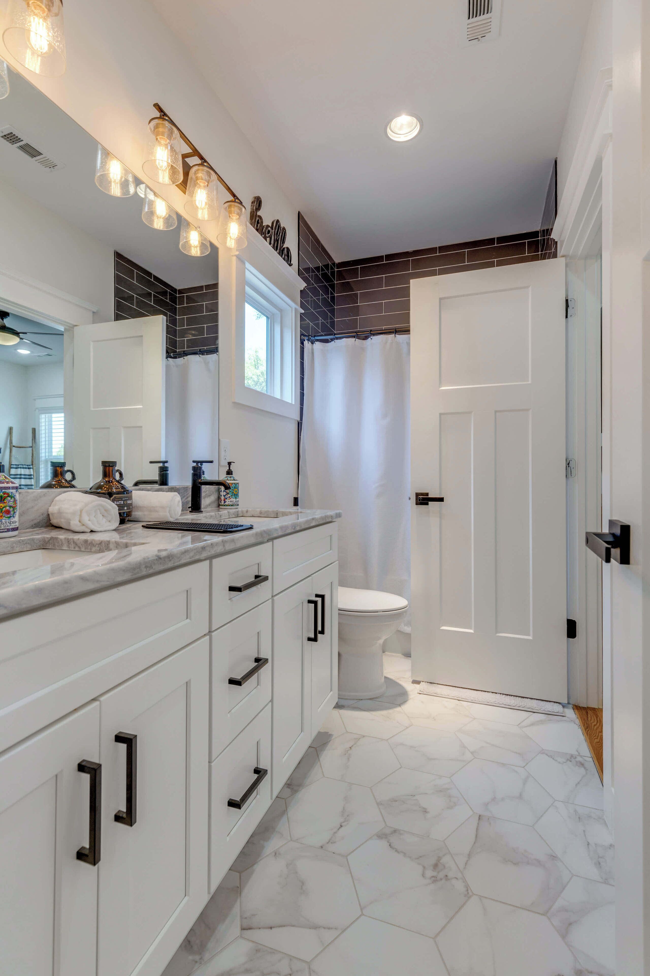 A modern bathroom with a white vanity, a large mirror, and a shower area.
