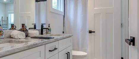 A modern bathroom with a white vanity, a large mirror, and a shower area.
