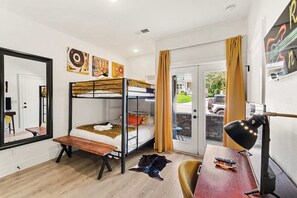 A room with a bunk bed, a desk with a lamp, a mirror, and artwork on the walls. - Beautiful Balcony! Sleeps 12! 4 Miles from Broadway (Nashville)