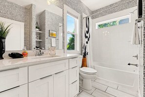 A modern bathroom with a large window, a shower, and a toilet.