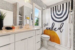 A bathroom with a mirror, sink, toilet, and a shower curtain with a sun design. - Beautiful Balcony! Sleeps 12! 4 Miles from Broadway (Nashville)