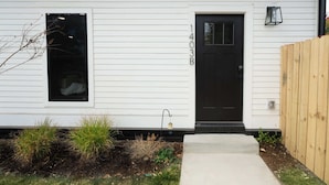 A white house with a black front door, number 403B, a small window, and a wooden fence. - Stylish Modern Bungalow in Nashville's 12 South (Nashville)