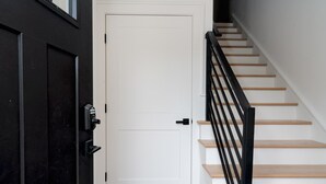 A staircase with wooden steps and black railings, leading to a white door with a black handle. - Stylish Modern Bungalow in Nashville's 12 South (Nashville)