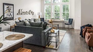 Una sala moderna con un sofá gris, una mesa de centro y un comedor con una mesa blanca.