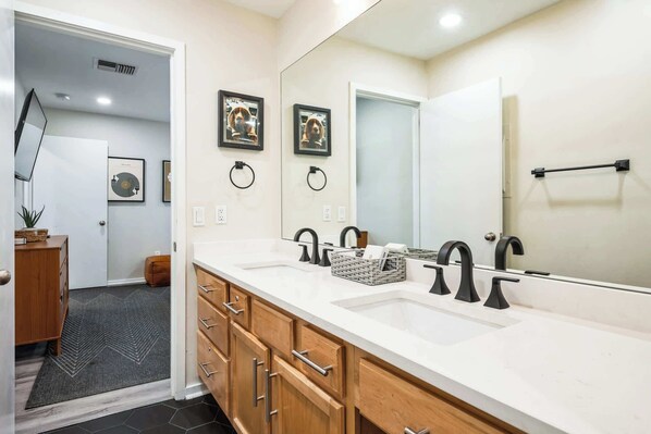 A modern bathroom with a large mirror, two sinks, and wooden cabinetry. - Downtown Riverfront 2BR Condo — Balcony, Sleeps 6 (Nashville)