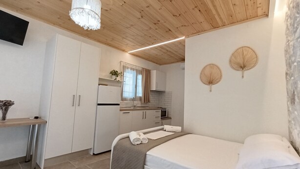 A compact bedroom with a bed, a bedside table, and a window. - Villa Marilou Fourka (Kassandra)