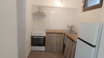 Een kleine keuken met een fornuis, oven en koelkast.