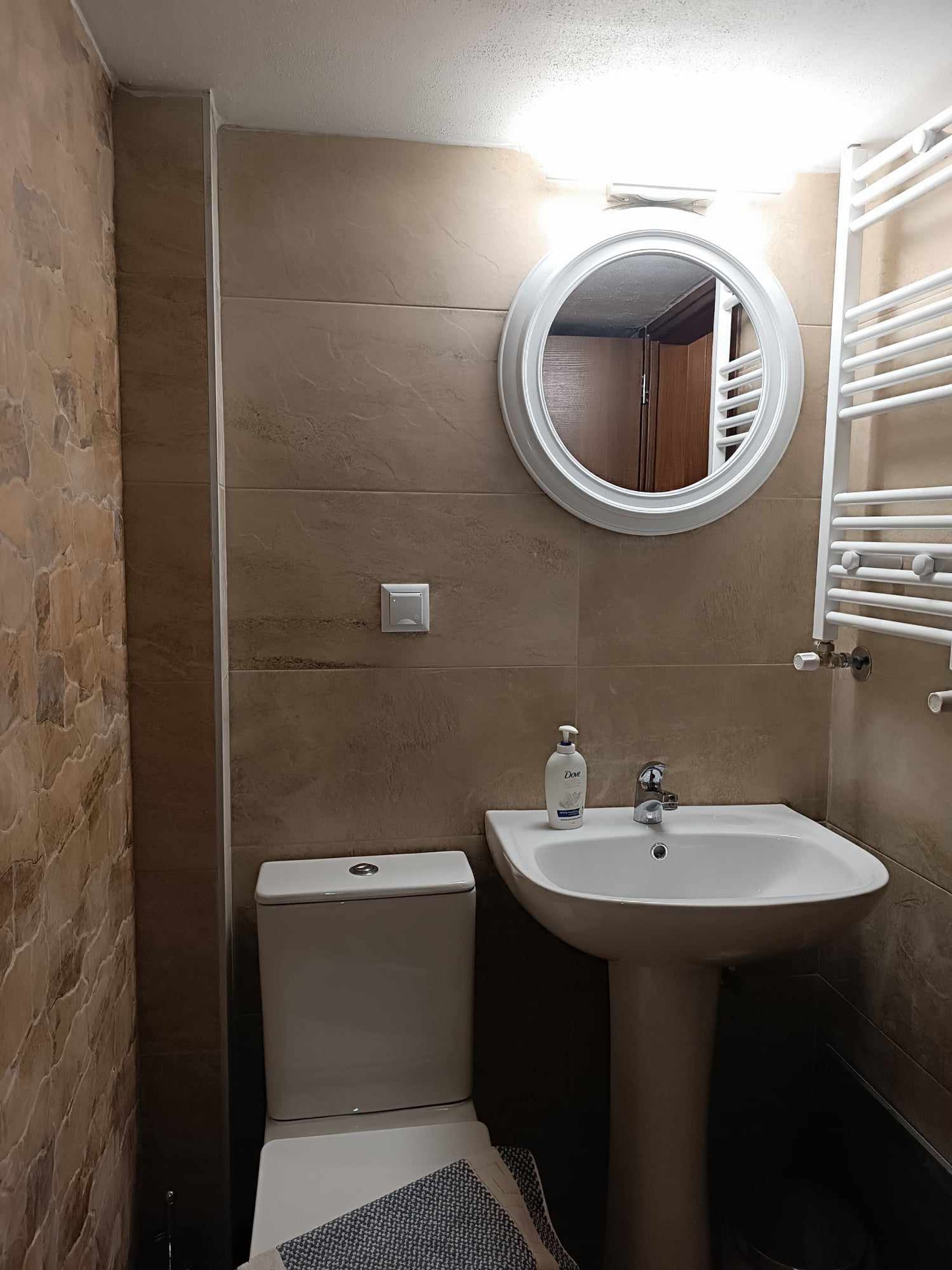 Un baño con inodoro, lavamanos y espejo.