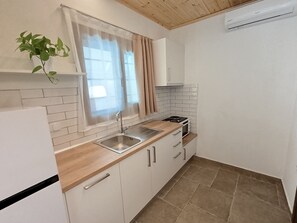 Cocina compacta con lavamanos, estufa y alacenas.