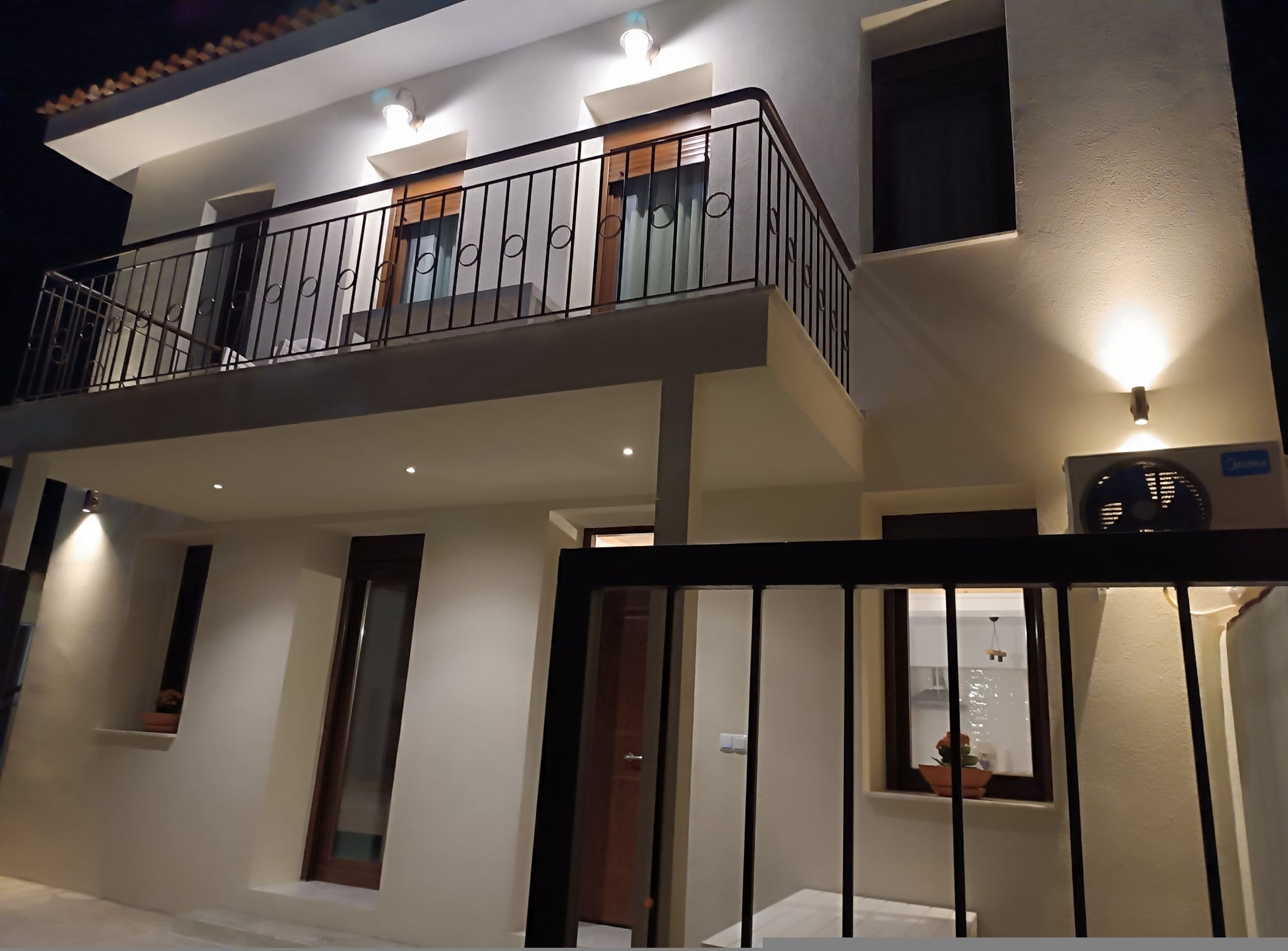 A two-story building with a balcony, a door, and a window.