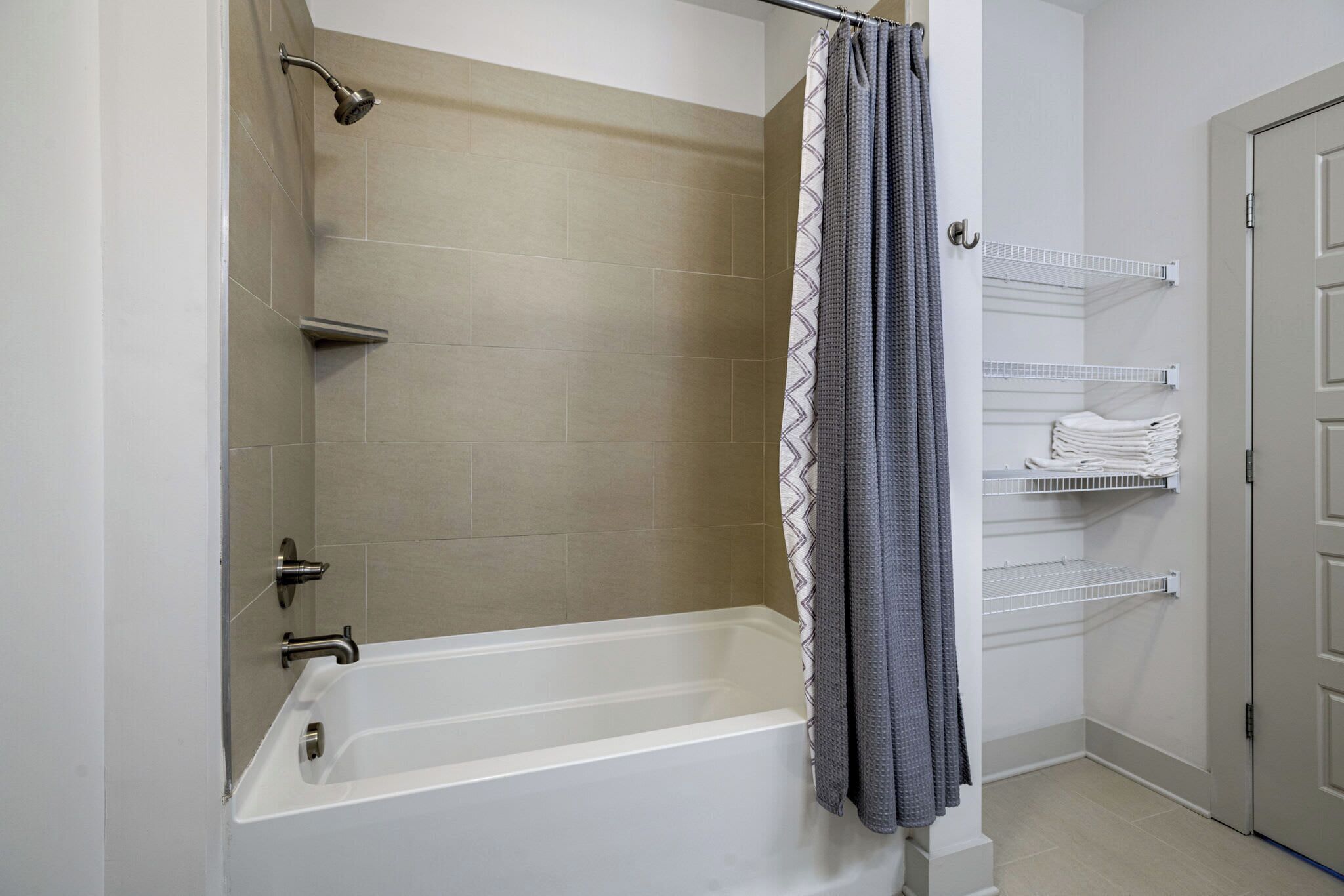 Une salle de bain équipée d’une baignoire, d’une douche et d’un porte-serviettes avec des serviettes pliées.
