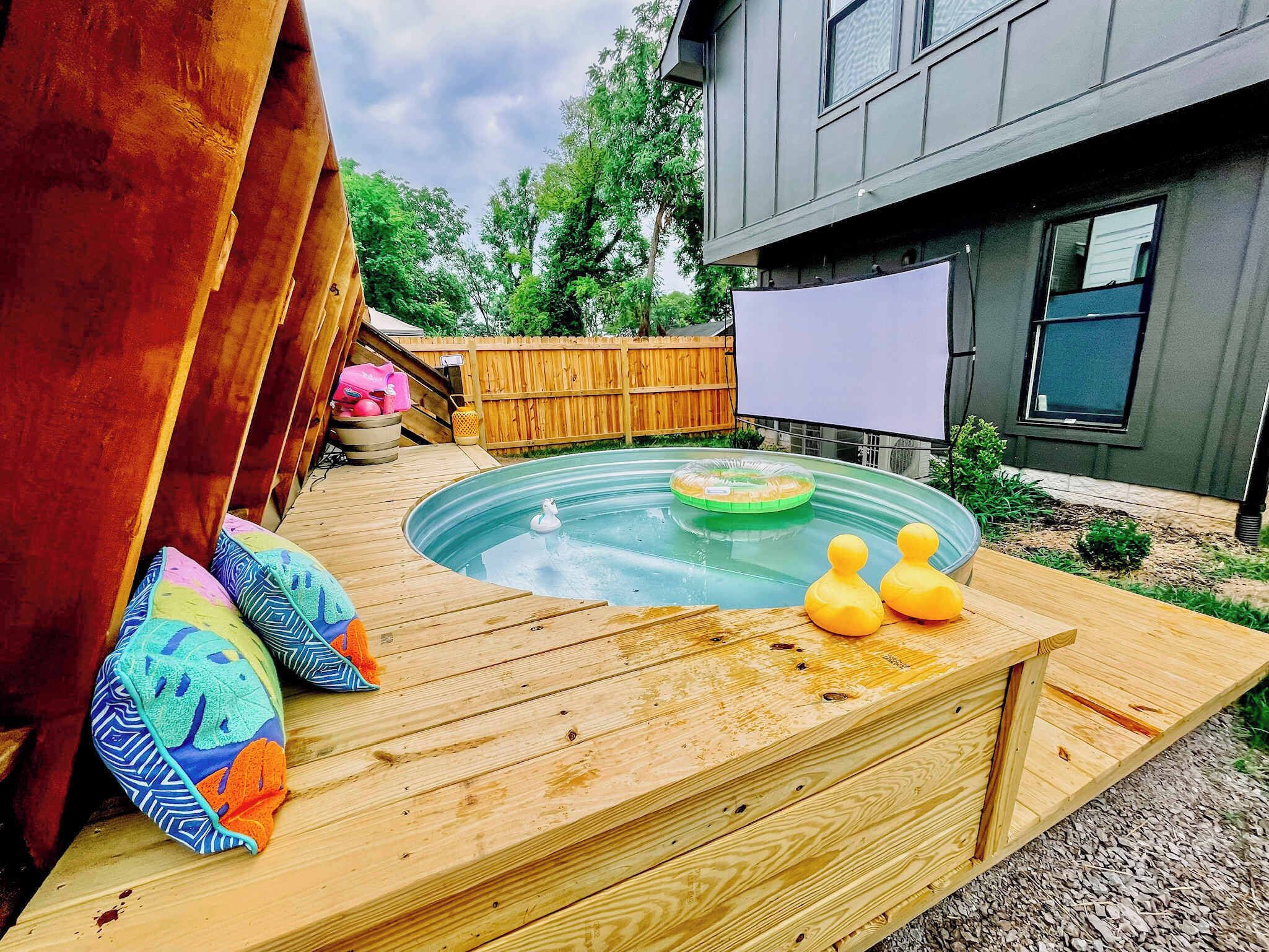 A wooden deck with a hot tub, two rubber ducks, and colorful cushions.
