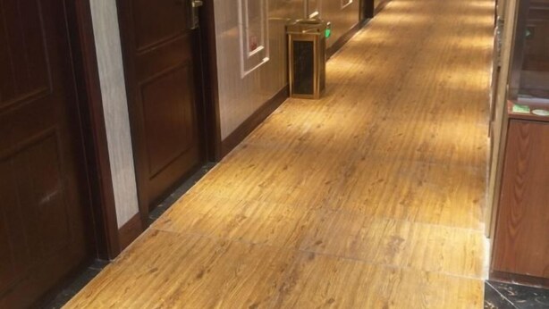 A hallway with wooden flooring and doors on both sides.