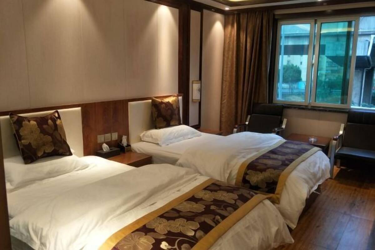Een hotelkamer met twee bedden, een bureau, een stoel en een raam met gordijnen.