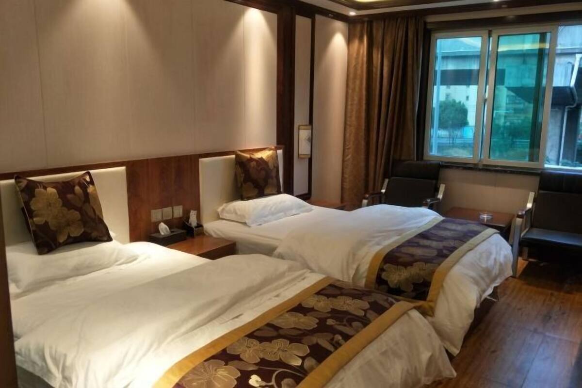 Een hotelkamer met twee bedden, een bureau, een stoel en een raam met gordijnen.